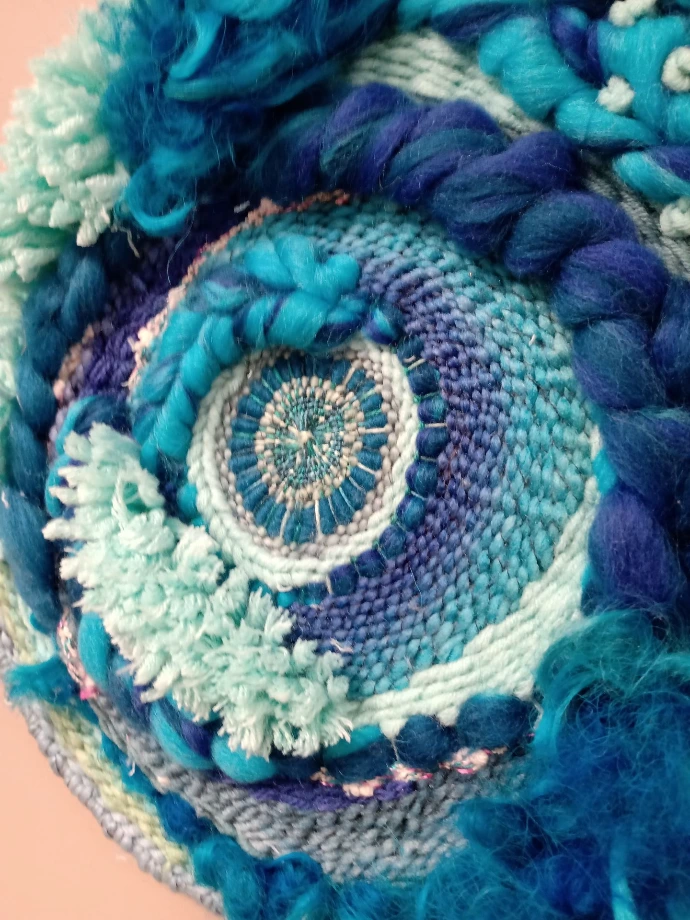 zoom sur une œuvre tissée ronde dans les tons bleus
