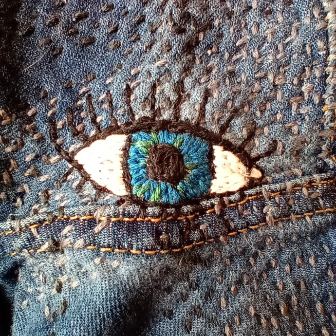 visible mending, broderie d'un œil sur un trou de pantalon