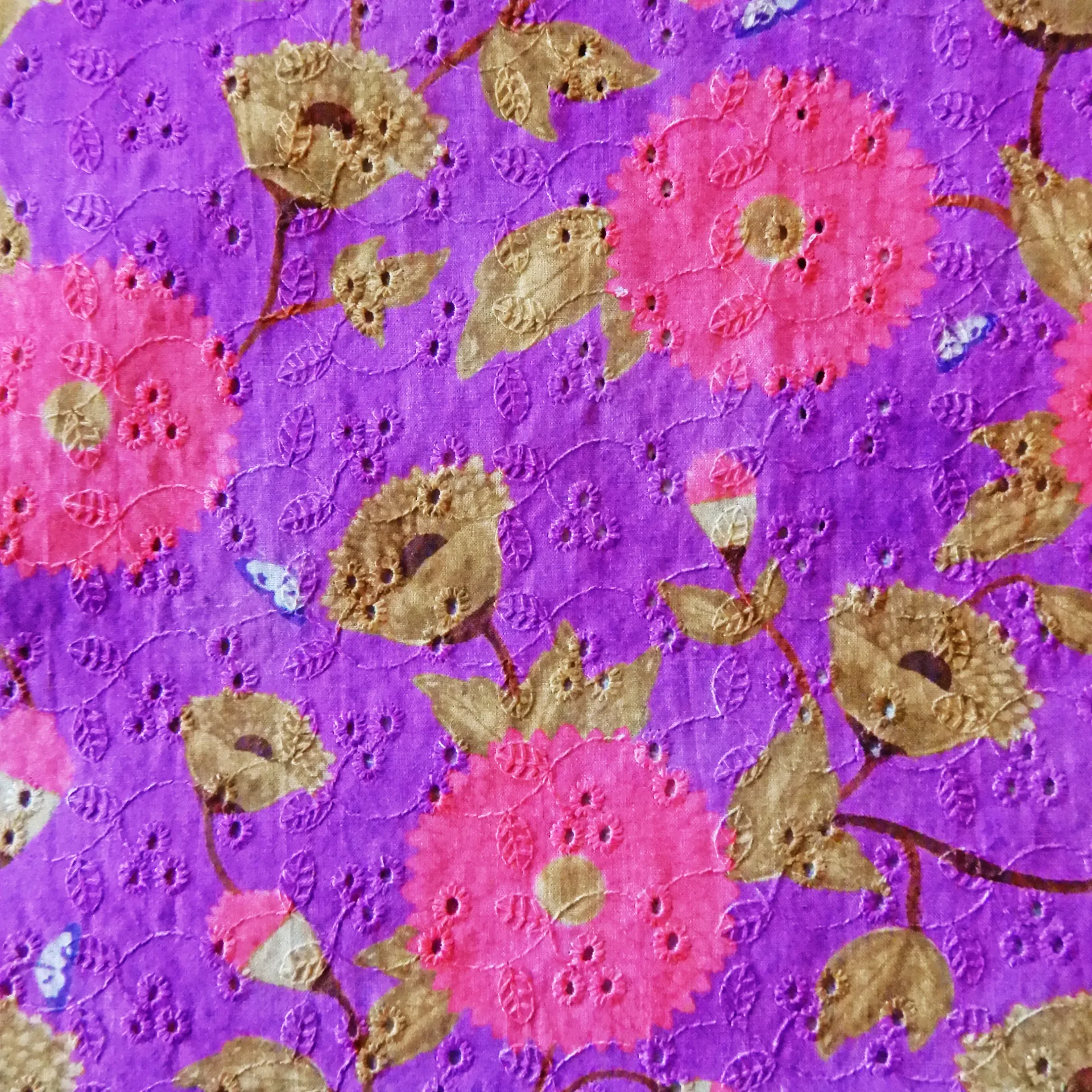 Fleurs roses et papillon sur un tissu brodé mauve