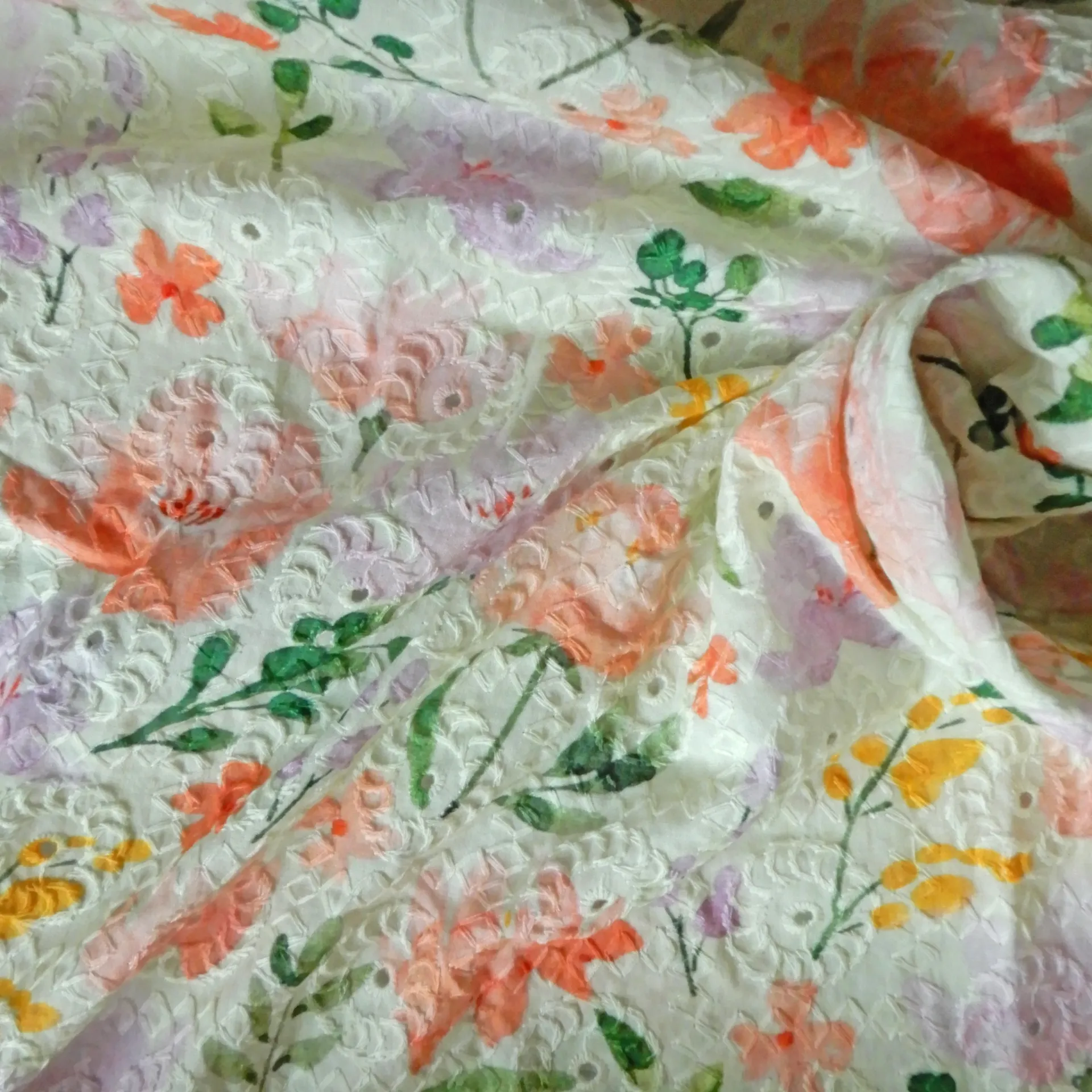 Fleurs roses imprimées sur un tissu brodé écru virant au vert clair