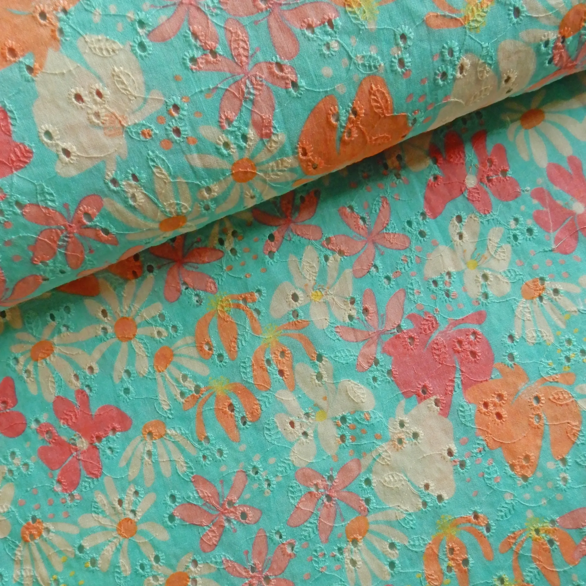 Fleurs rose-corail imprimées sur un tissu brodé bleu
